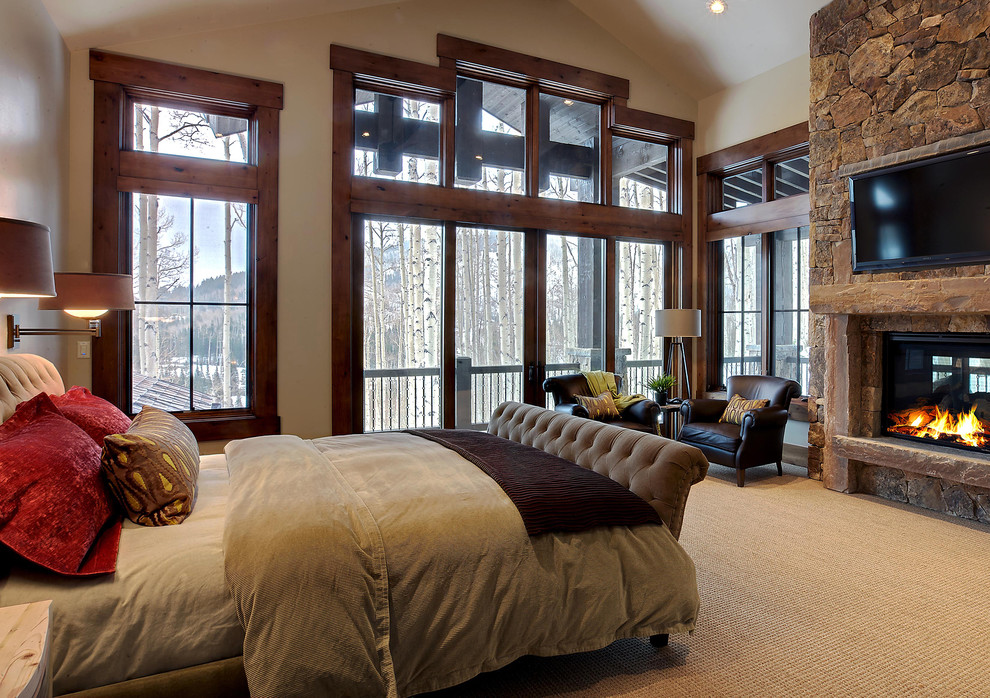 На фото: спальня в стиле рустика с бежевыми стенами, ковровым покрытием, стандартным камином и фасадом камина из камня