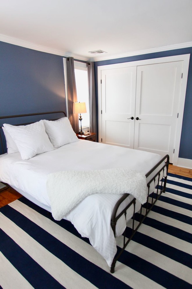 Immagine di una camera degli ospiti country di medie dimensioni con pareti blu, parquet chiaro e pavimento marrone