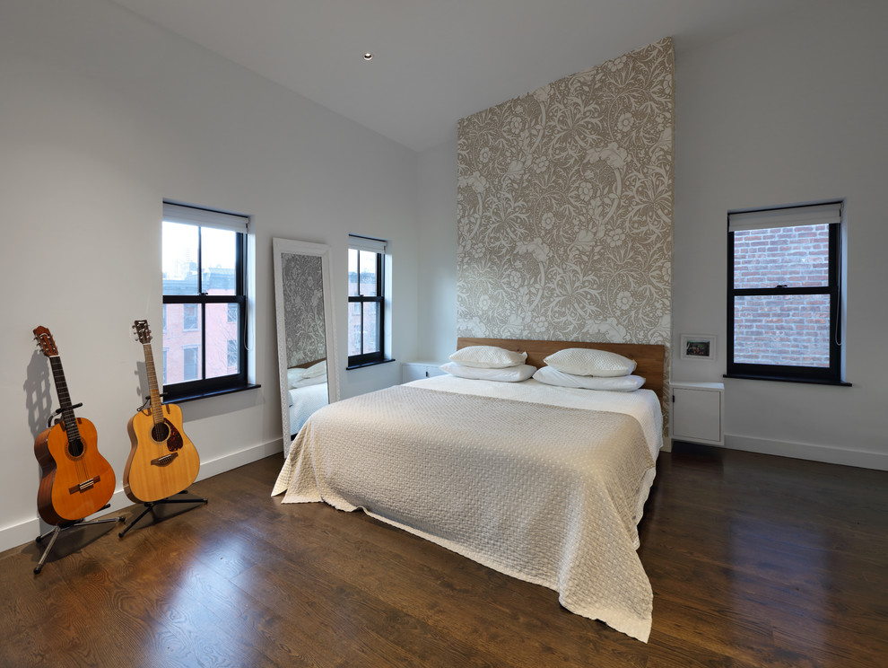 This is an example of a large modern master bedroom in New York with white walls, dark hardwood flooring, no fireplace, wallpapered walls and brown floors.