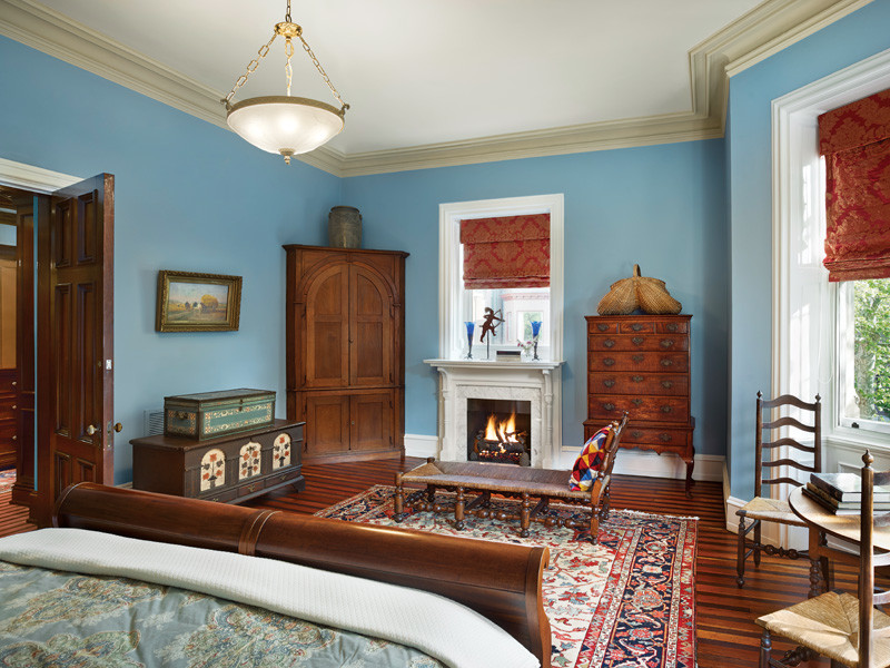 Modelo de dormitorio principal clásico grande con paredes azules, suelo de madera oscura, todas las chimeneas y marco de chimenea de yeso