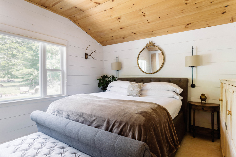 Imagen de dormitorio principal de estilo de casa de campo pequeño con paredes blancas, suelo de madera clara, estufa de leña y suelo blanco