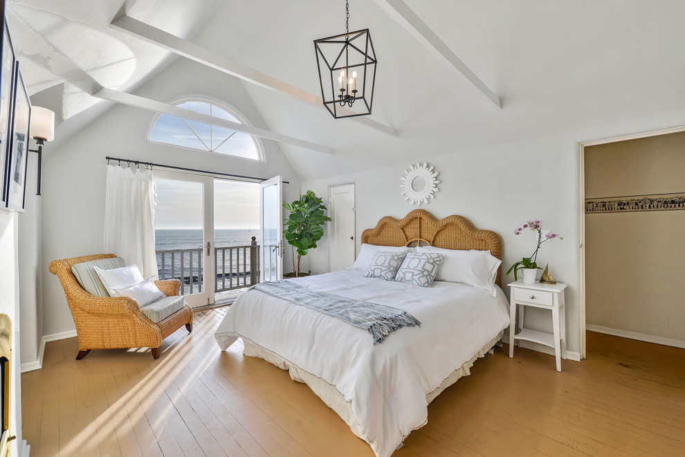 Modelo de dormitorio principal marinero con paredes grises, suelo de madera en tonos medios, todas las chimeneas y suelo beige