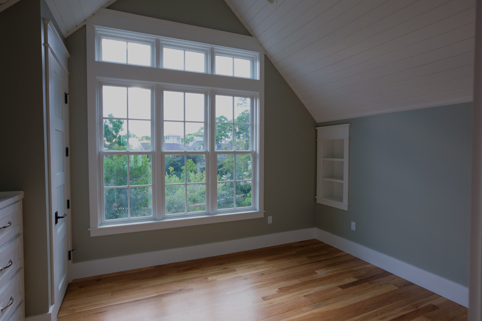 Ejemplo de habitación de invitados costera de tamaño medio sin chimenea con paredes verdes y suelo de madera clara