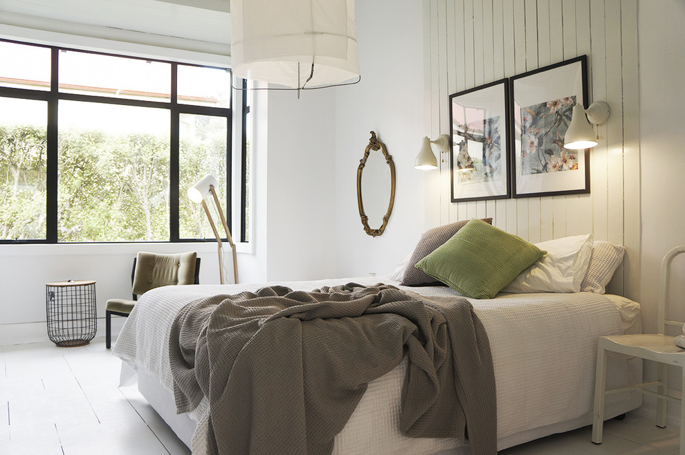 Minimalistisk inredning av ett sovrum, med vita väggar, målat trägolv och vitt golv