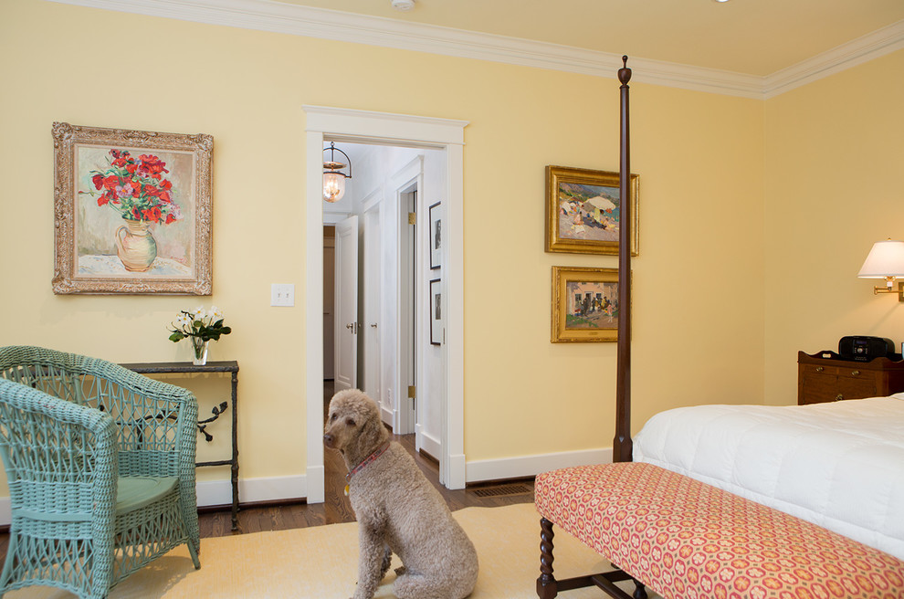 Imagen de dormitorio principal tradicional grande con paredes amarillas y suelo de madera en tonos medios
