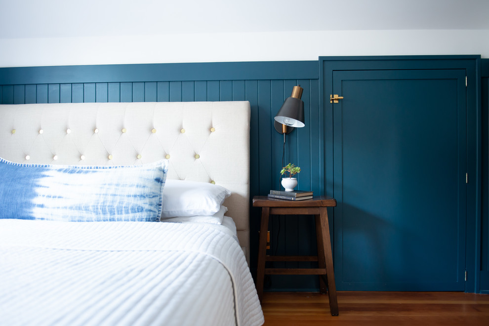 Modelo de dormitorio principal tradicional de tamaño medio sin chimenea con paredes azules, suelo de madera en tonos medios y suelo marrón