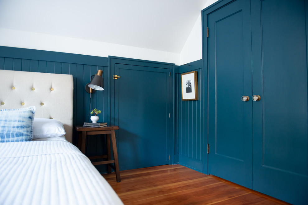 Réalisation d'une chambre parentale tradition de taille moyenne avec un mur bleu, un sol en bois brun, aucune cheminée et un sol marron.