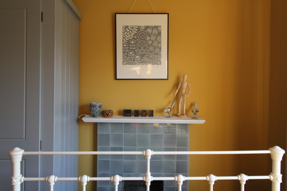 Inspiration för ett litet minimalistiskt gästrum, med gula väggar, mörkt trägolv, en standard öppen spis och en spiselkrans i trä