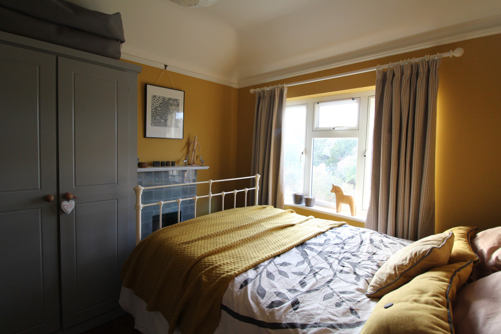 Foto de habitación de invitados nórdica pequeña con paredes amarillas, suelo de madera oscura, todas las chimeneas y marco de chimenea de baldosas y/o azulejos