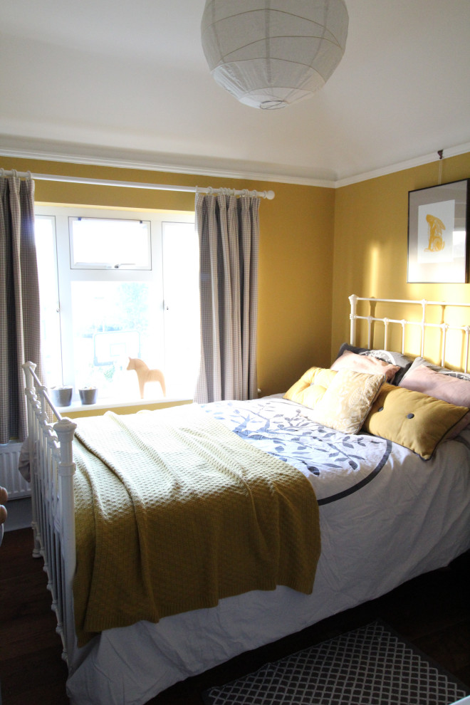 Example of a small danish guest dark wood floor bedroom design in Cambridgeshire with yellow walls, a standard fireplace and a tile fireplace