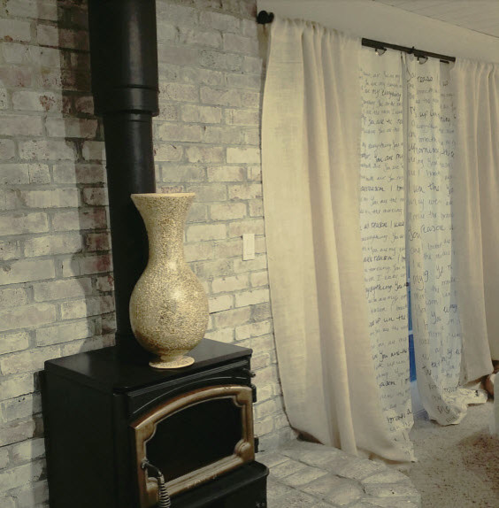 На фото: большая хозяйская спальня в стиле ретро с белыми стенами, ковровым покрытием, печью-буржуйкой и фасадом камина из кирпича с
