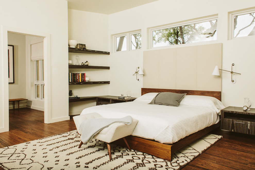 This is an example of a modern bedroom in Austin with white walls and dark hardwood flooring.