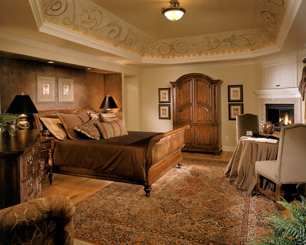 Immagine di una camera da letto classica con pareti beige, camino ad angolo e pavimento marrone