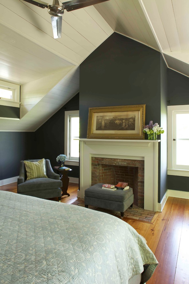 Landhaus Schlafzimmer mit Kaminumrandung aus Backstein, grauer Wandfarbe, braunem Holzboden und Kamin in New York