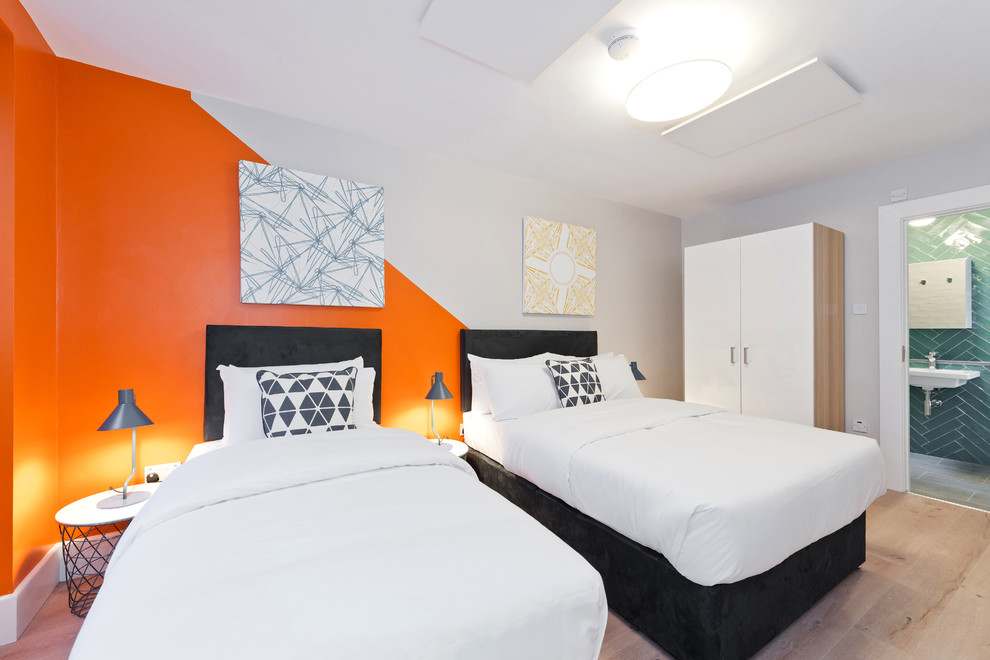 Ejemplo de habitación de invitados contemporánea de tamaño medio sin chimenea con parades naranjas, suelo beige y suelo laminado