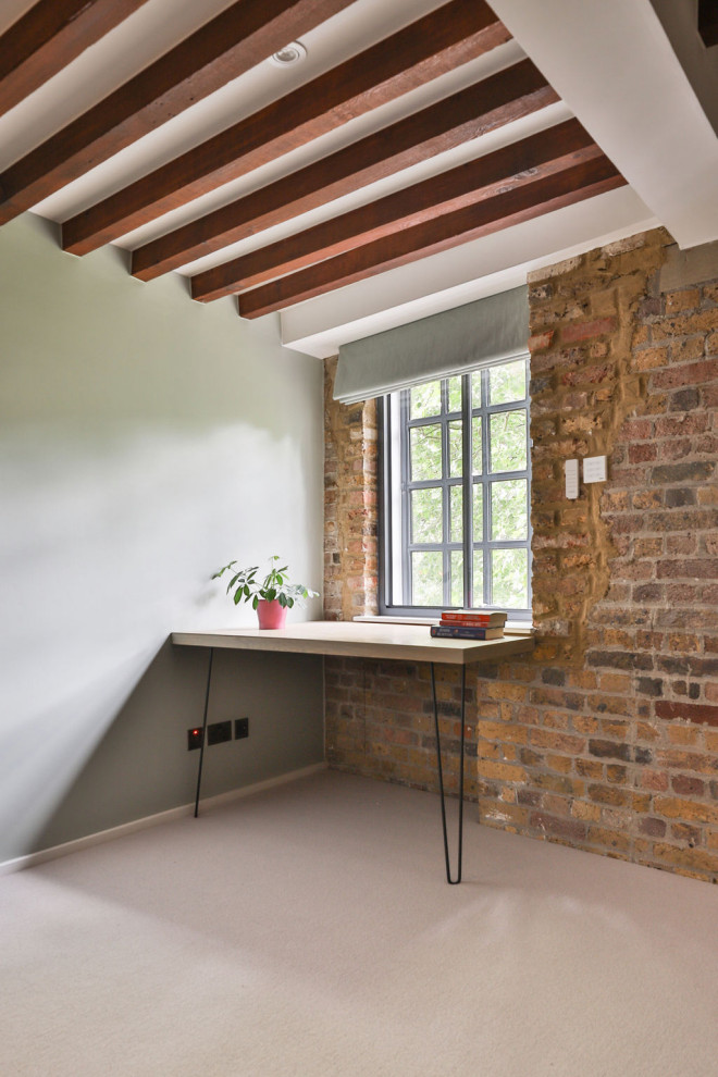 Aménagement d'une chambre moderne de taille moyenne avec un mur vert, un sol gris, poutres apparentes et un mur en parement de brique.