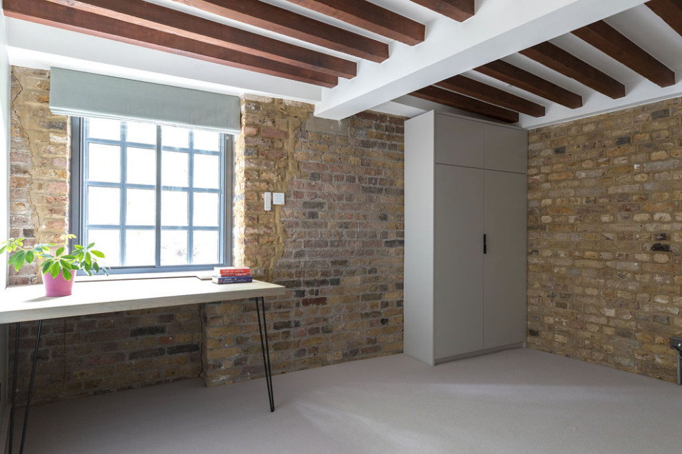 Cette photo montre une chambre moderne de taille moyenne avec un mur vert, un sol gris, poutres apparentes et un mur en parement de brique.