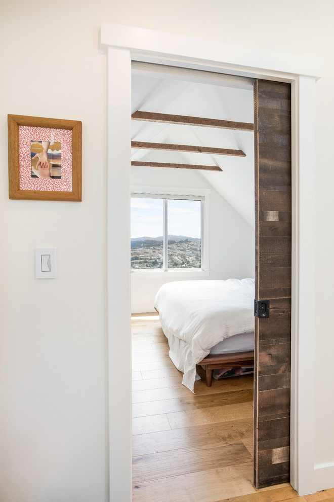 Modelo de dormitorio principal nórdico de tamaño medio con paredes blancas, suelo de madera en tonos medios y suelo marrón