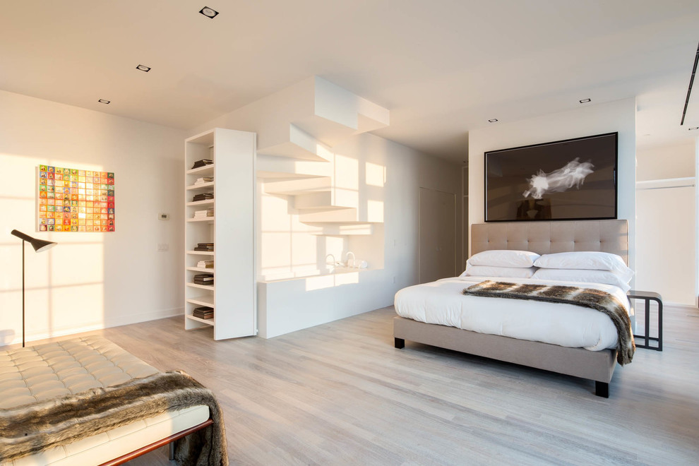 Contemporary bedroom in New York with white walls and light hardwood flooring.