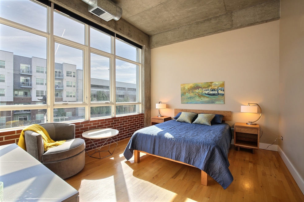 Imagen de dormitorio urbano con paredes beige y suelo de madera en tonos medios