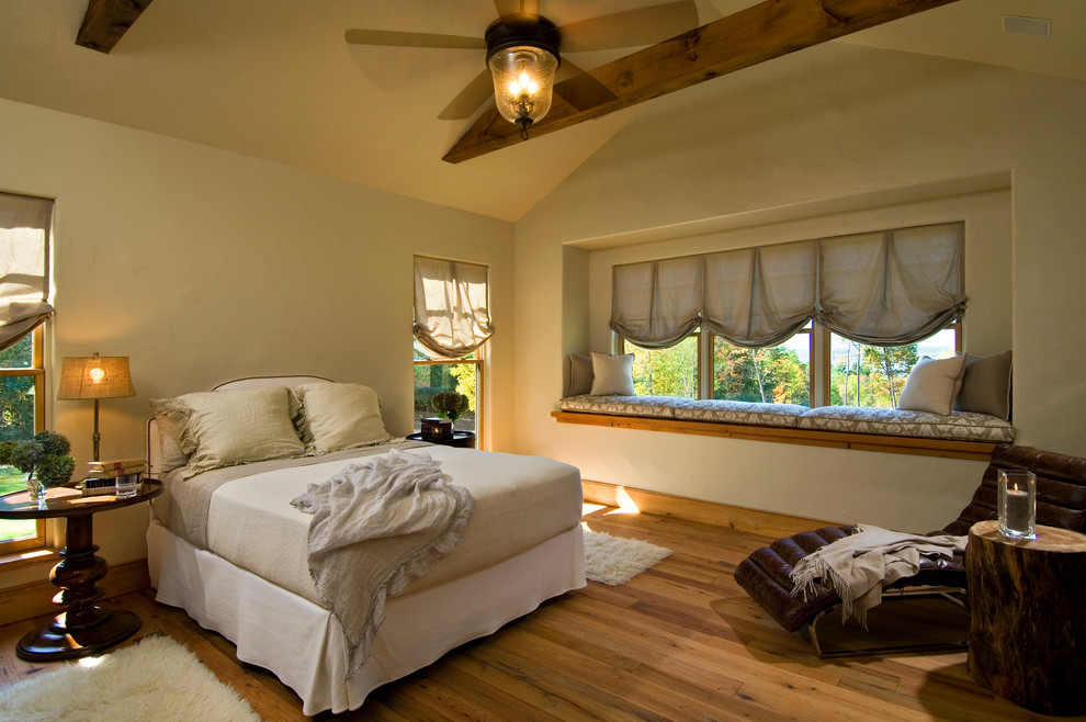 Imagen de dormitorio rural con paredes beige y suelo de madera en tonos medios
