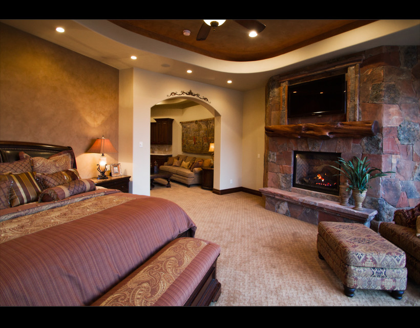 Foto de dormitorio principal clásico grande con paredes beige, moqueta, todas las chimeneas y marco de chimenea de piedra
