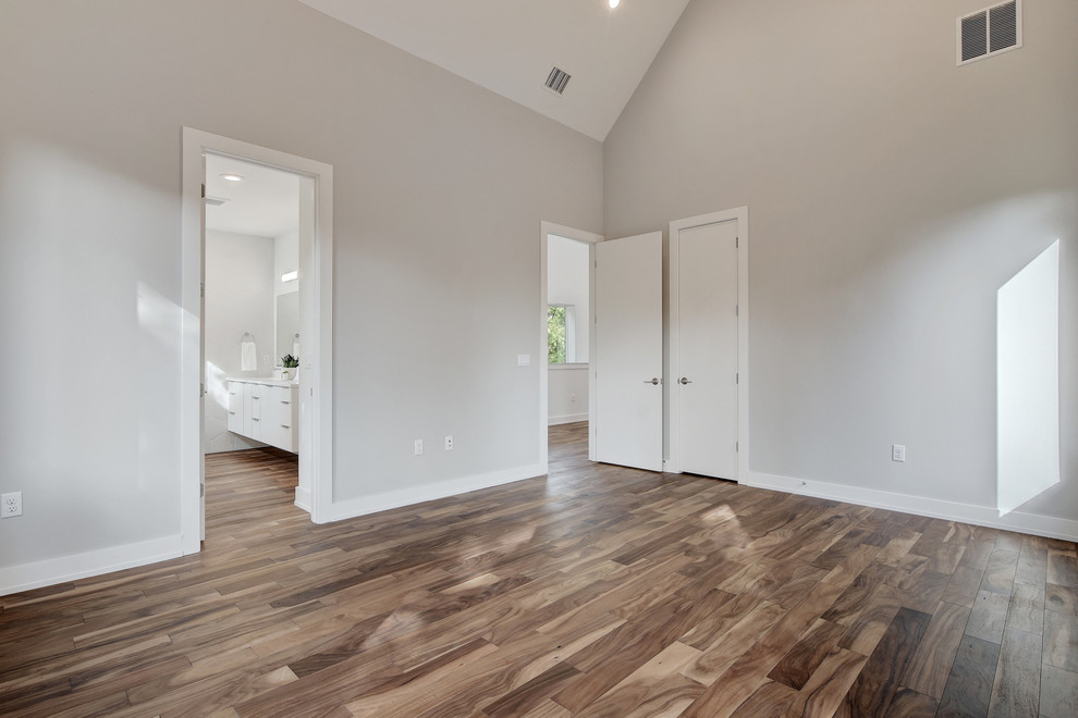 Modelo de dormitorio principal minimalista de tamaño medio con paredes grises, suelo de madera en tonos medios y suelo marrón