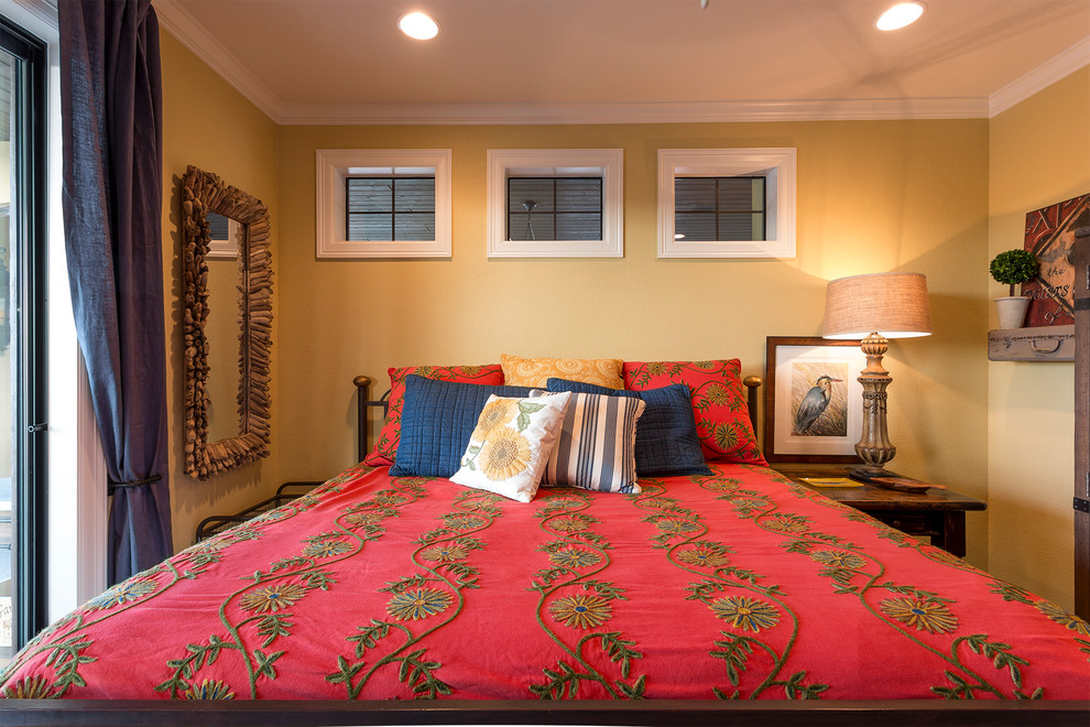 Mittelgroßes Mediterranes Hauptschlafzimmer mit gelber Wandfarbe, dunklem Holzboden und braunem Boden in Austin