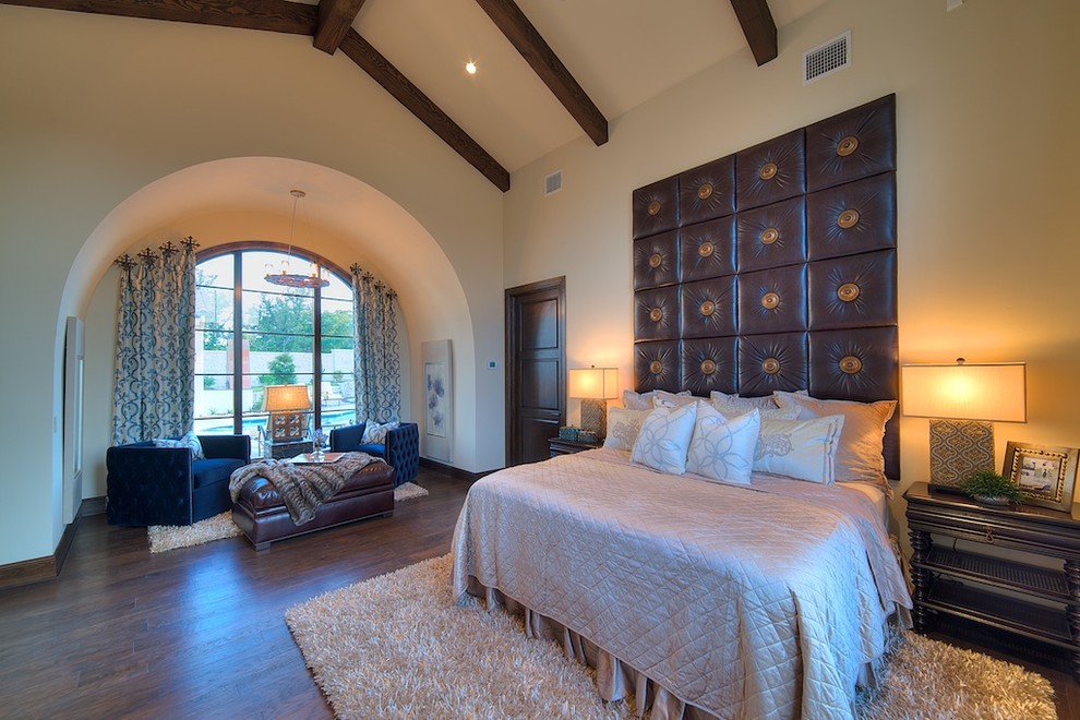 Ejemplo de dormitorio principal mediterráneo grande con suelo de madera oscura, paredes beige y suelo marrón