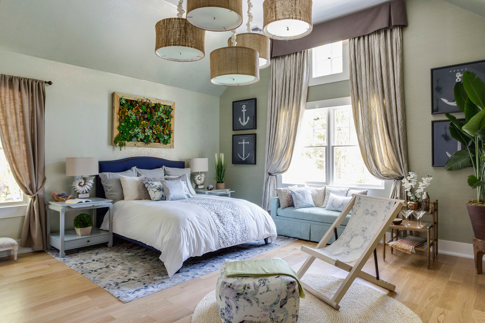 Modelo de habitación de invitados tradicional de tamaño medio sin chimenea con paredes verdes y suelo de madera clara