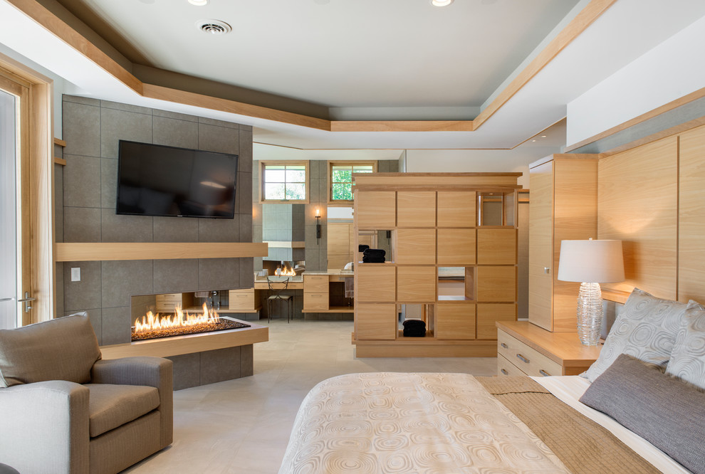 Large contemporary master bedroom in Minneapolis with white walls, porcelain flooring, a tiled fireplace surround, a two-sided fireplace and feature lighting.