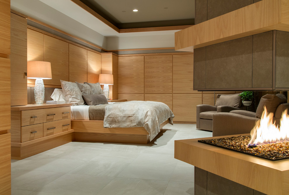 Ejemplo de dormitorio principal contemporáneo grande con paredes blancas, suelo de baldosas de porcelana, marco de chimenea de baldosas y/o azulejos y chimenea de esquina