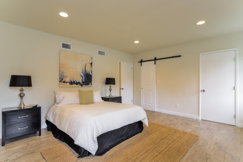 Inspiration pour une chambre d'amis design de taille moyenne avec un mur beige et parquet clair.