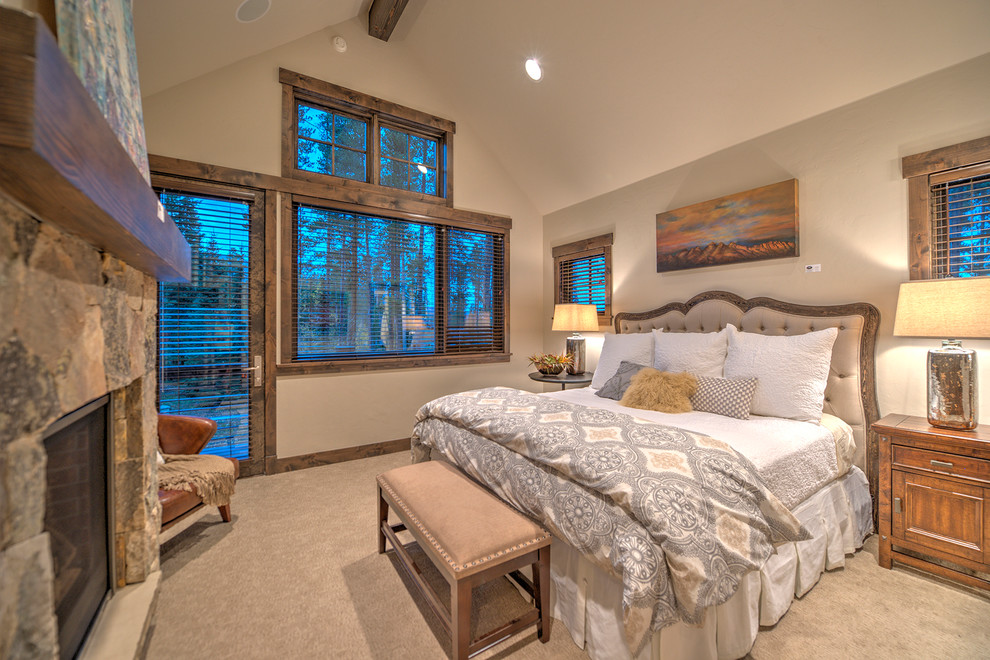 На фото: хозяйская спальня в стиле рустика с бежевыми стенами, ковровым покрытием, стандартным камином и фасадом камина из камня с