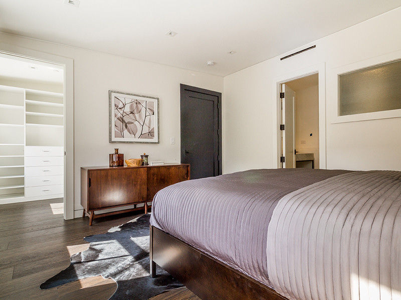 Foto de habitación de invitados moderna con paredes blancas, suelo de madera oscura y suelo marrón