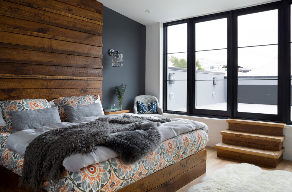 Ejemplo de dormitorio principal actual grande sin chimenea con paredes grises, suelo de madera clara y suelo beige