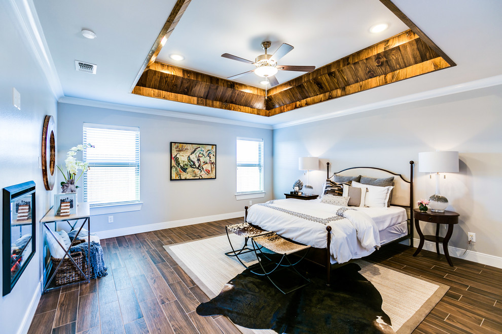 オースティンにある広いトランジショナルスタイルのおしゃれな主寝室 (グレーの壁、セラミックタイルの床、両方向型暖炉、漆喰の暖炉まわり、茶色い床) のレイアウト