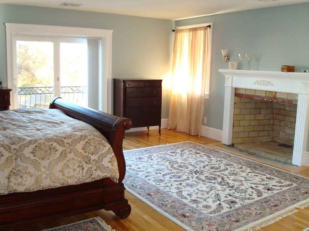 Ejemplo de dormitorio principal clásico de tamaño medio con suelo de madera clara, todas las chimeneas, paredes azules, marco de chimenea de yeso y suelo marrón
