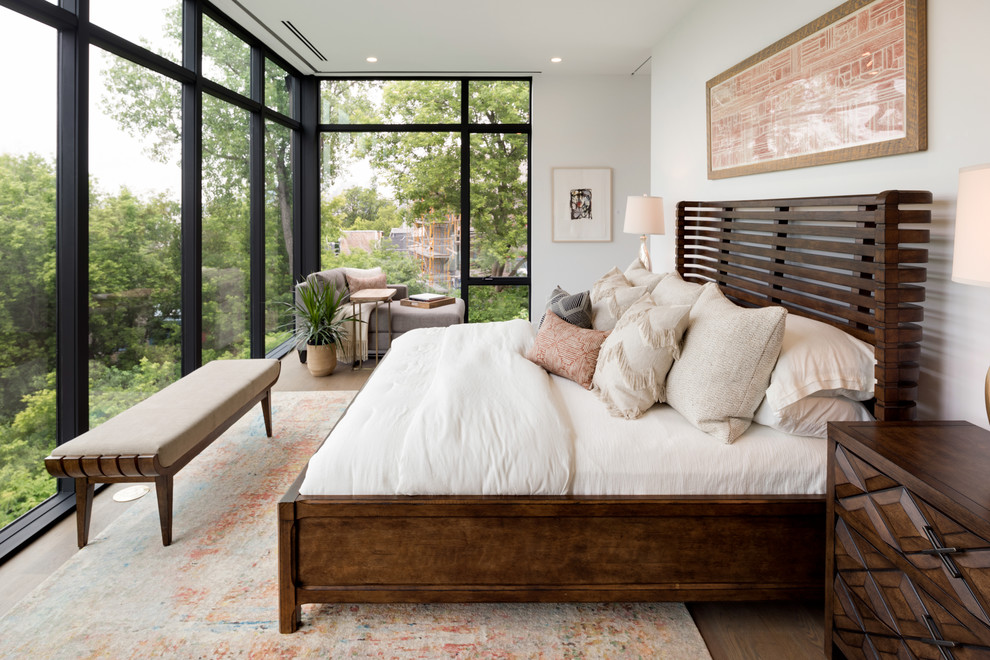 Modelo de dormitorio principal minimalista grande con paredes blancas, suelo de madera clara y suelo gris