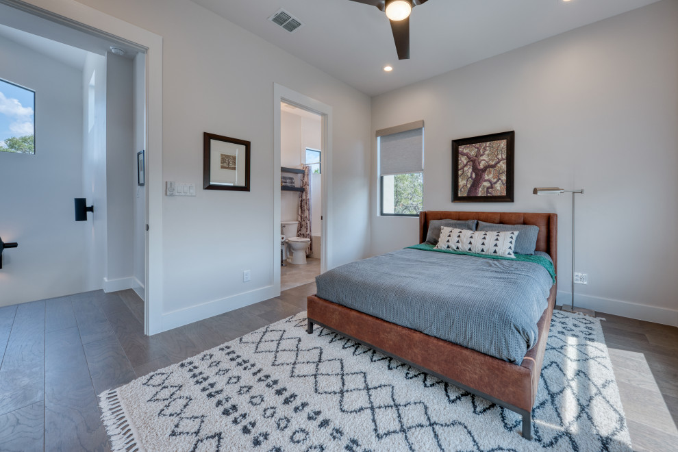 Diseño de dormitorio principal minimalista grande sin chimenea con paredes grises, suelo de madera en tonos medios y suelo gris