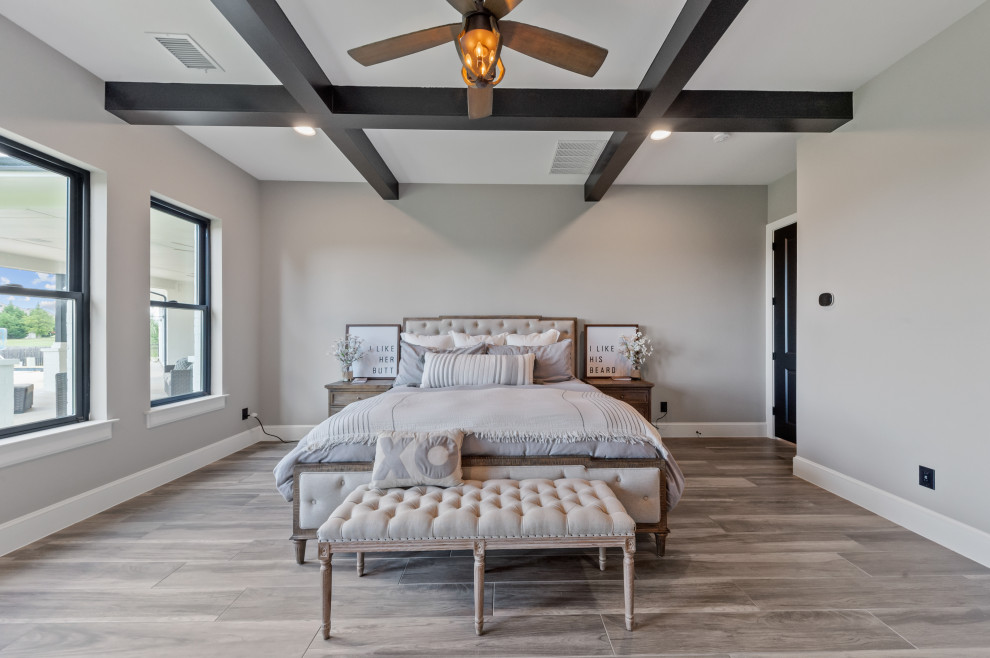 Diseño de dormitorio principal campestre de tamaño medio con paredes grises, suelo de madera en tonos medios, suelo marrón y vigas vistas