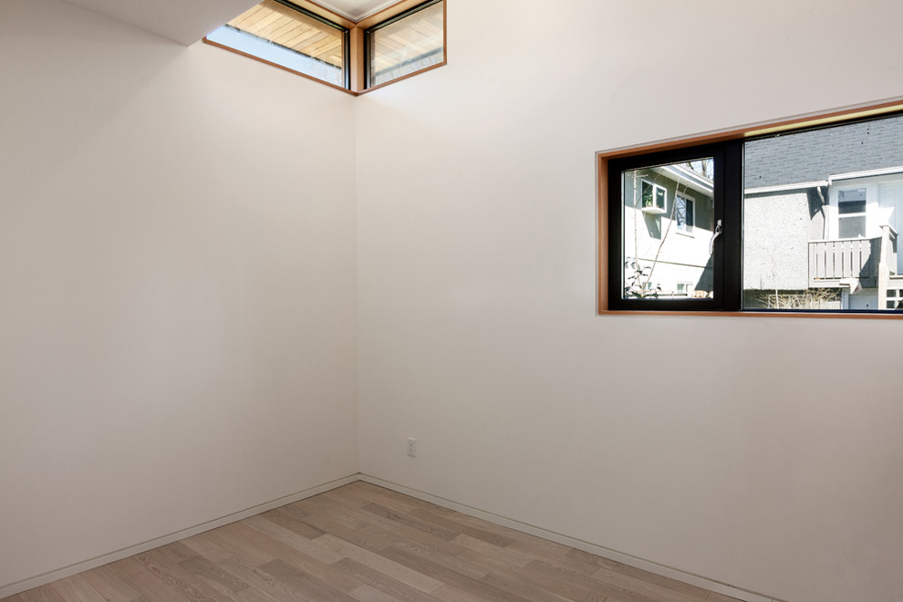 Modelo de dormitorio principal con paredes blancas y suelo de madera clara