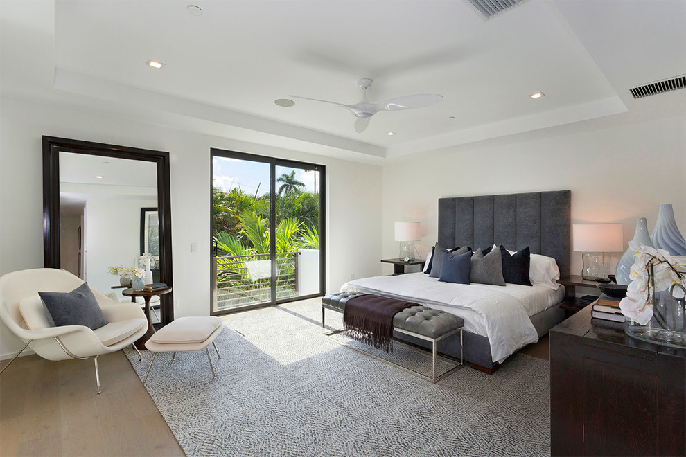 Photo of a contemporary master and grey and brown bedroom in Miami with white walls, medium hardwood flooring and brown floors.