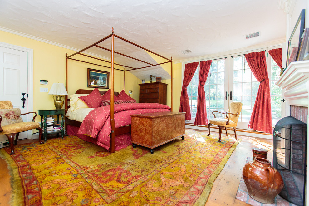 Example of a large classic master medium tone wood floor bedroom design in Boston with yellow walls, a standard fireplace and a wood fireplace surround