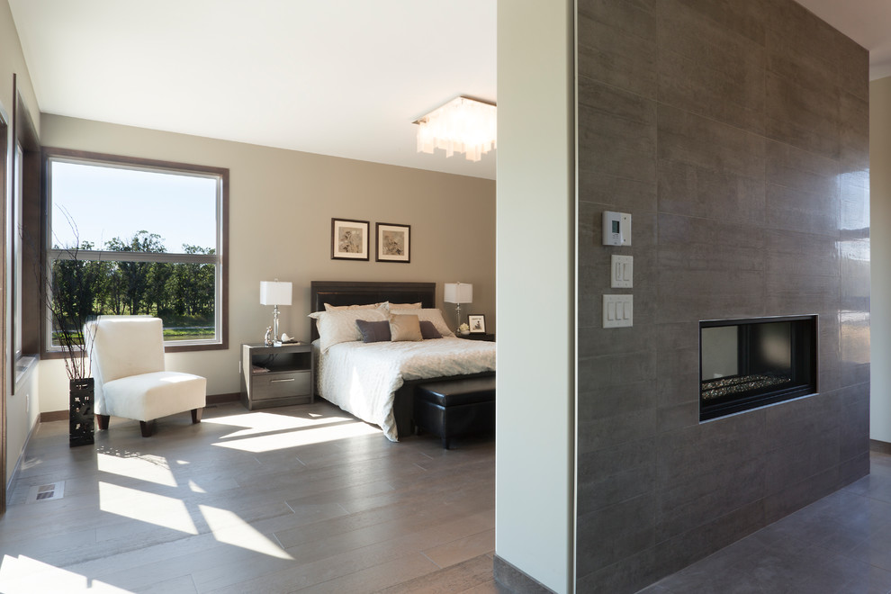 Immagine di una camera da letto design con pareti marroni, camino bifacciale, cornice del camino piastrellata e pavimento marrone
