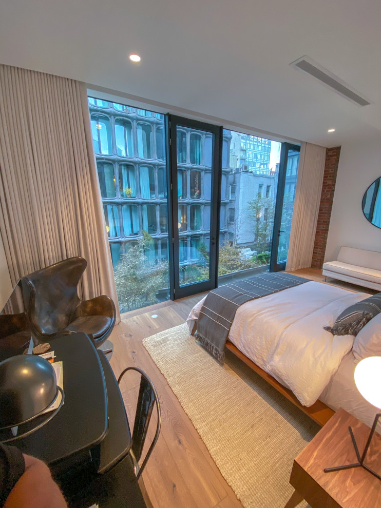 Modelo de dormitorio principal de tamaño medio con paredes blancas, suelo de madera clara y suelo beige