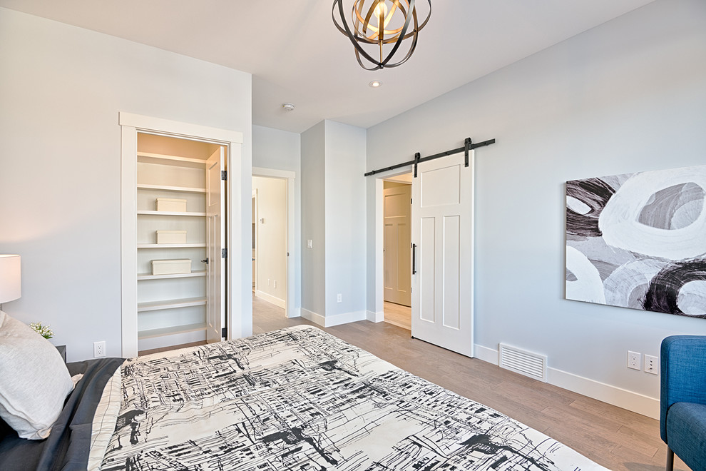 Diseño de dormitorio principal de estilo americano sin chimenea con paredes grises, suelo de madera clara y suelo marrón