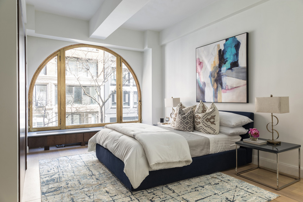 Contemporary bedroom in New York with white walls, medium hardwood flooring and brown floors.