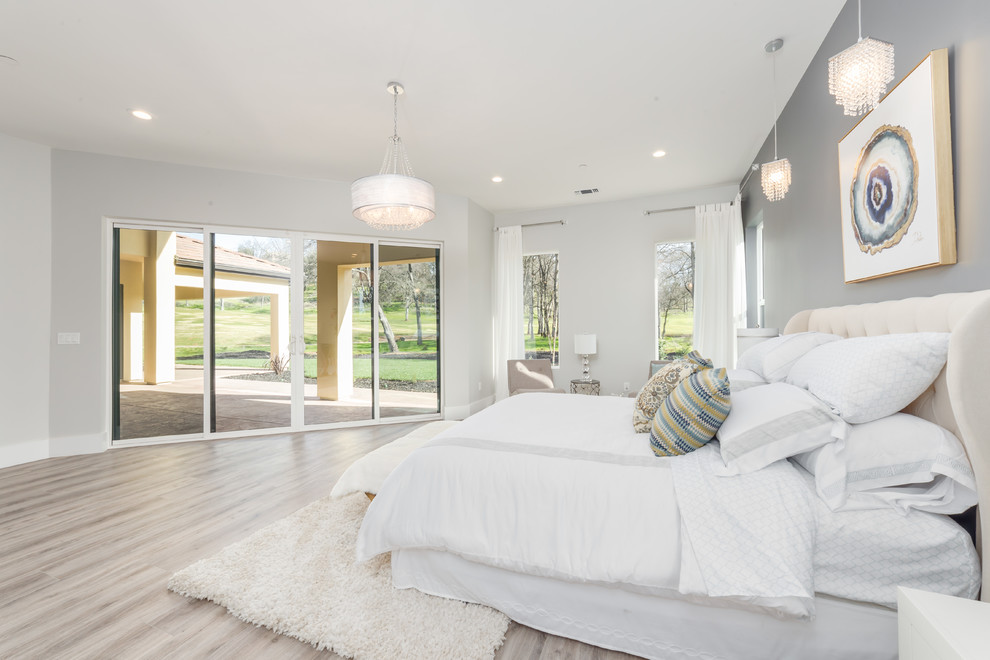 Ejemplo de dormitorio principal moderno grande sin chimenea con paredes grises, suelo de madera clara y suelo beige