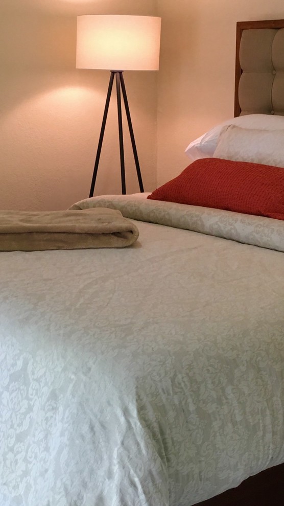 Modelo de dormitorio principal actual de tamaño medio sin chimenea con paredes beige, suelo de travertino y suelo beige
